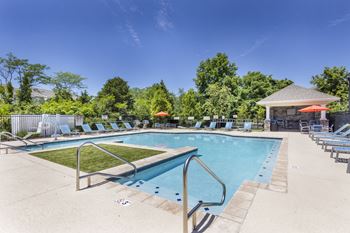 A large outdoor swimming pool surrounded by lounge chairs and umbrellas.